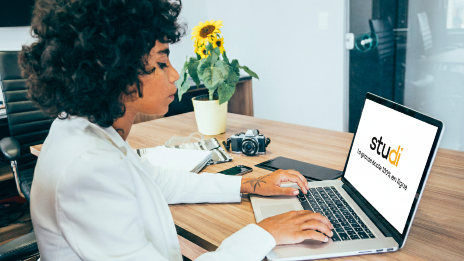 Une jeune femme devant son ordinateur avec le logo de Studi sur son écran